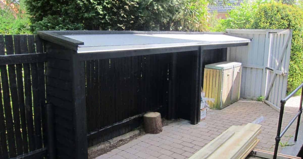 Skur konstrueret af et professionelt tømrerfirma i mørkt træ med tag